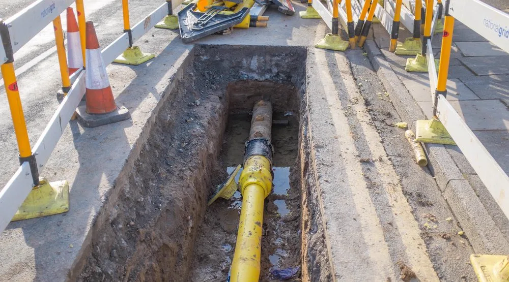 Trench cut through paving for a channel drain connected to underground pipework