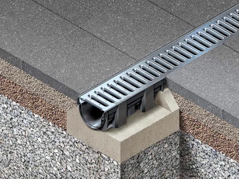 Cutaway of a channel drain set in a concrete bed beneath pavers, channel drains Brisbane