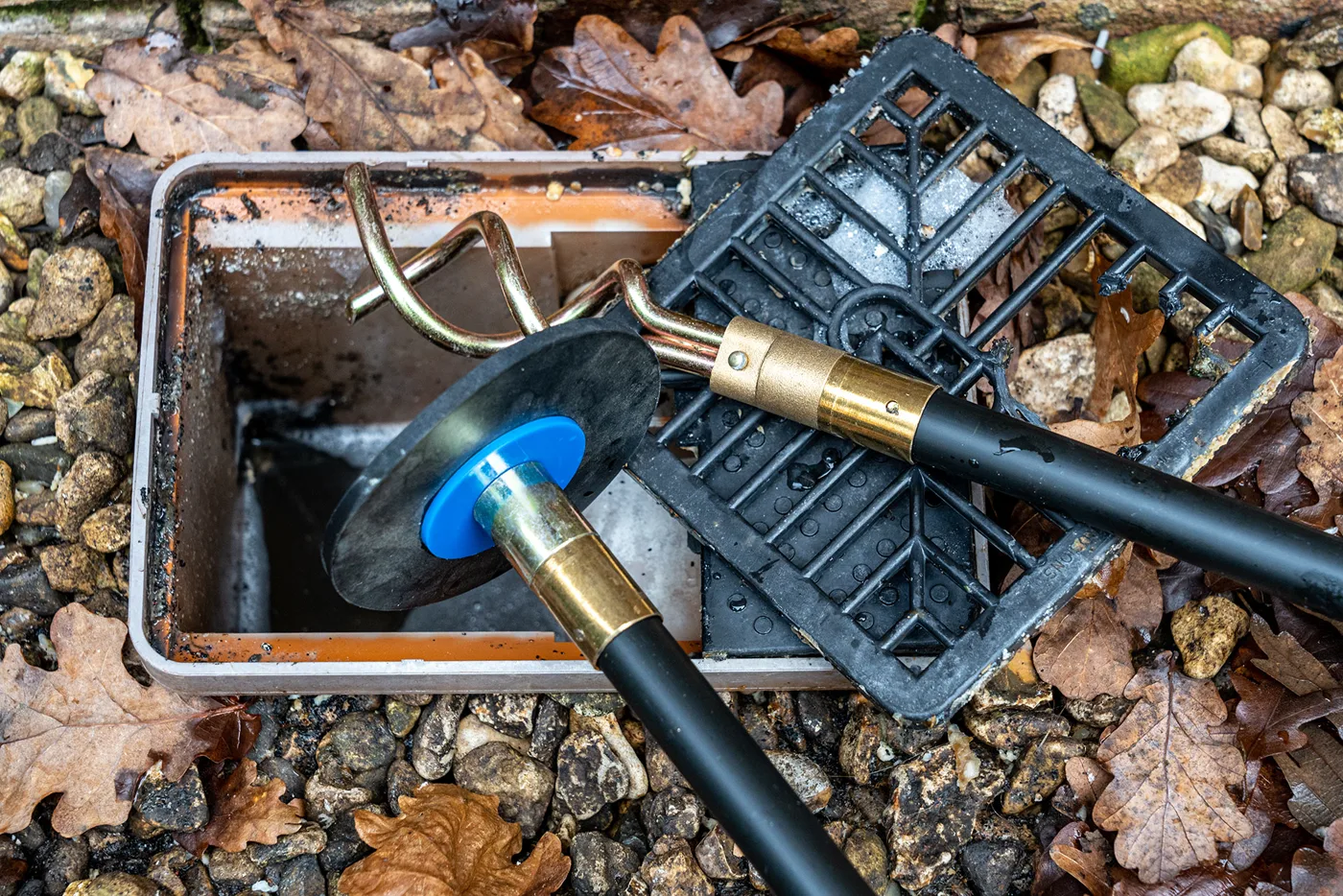 Jetting hose fed into a garden drainage pit to clear a blocked drain