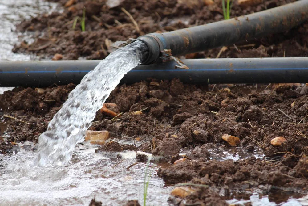 Water discharging hard from a stormwater pipe onto wet ground